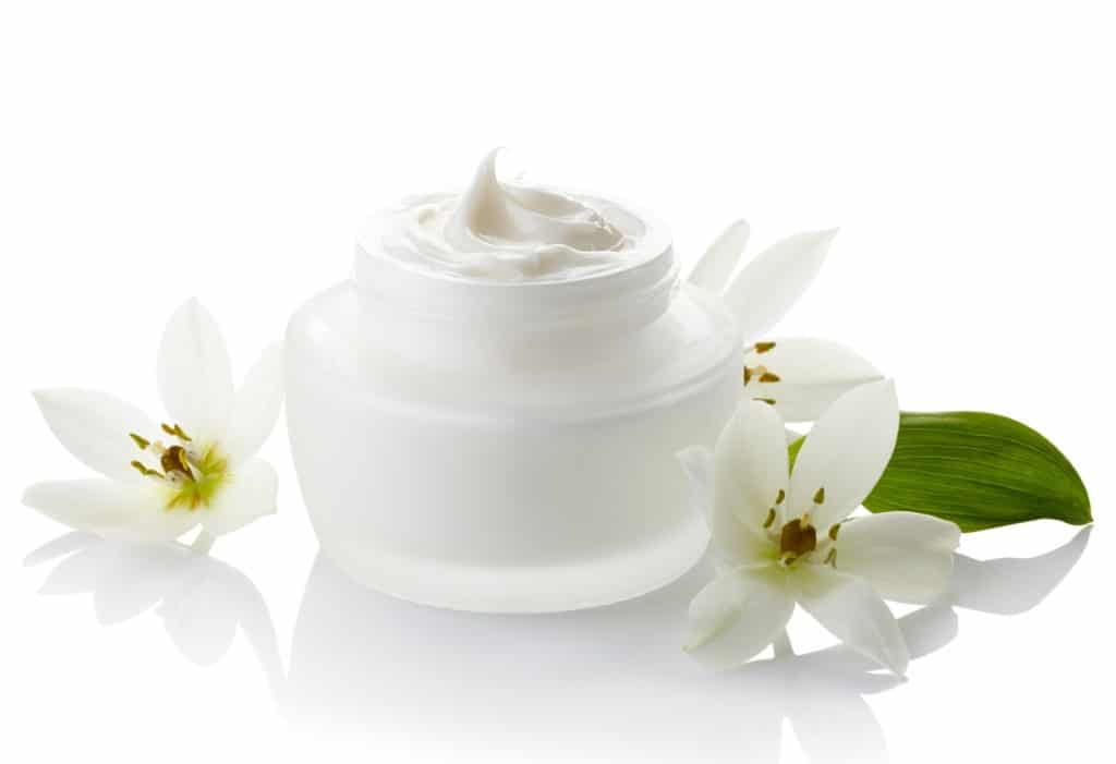 White jar of cosmetic cream and flowers isolated on white background