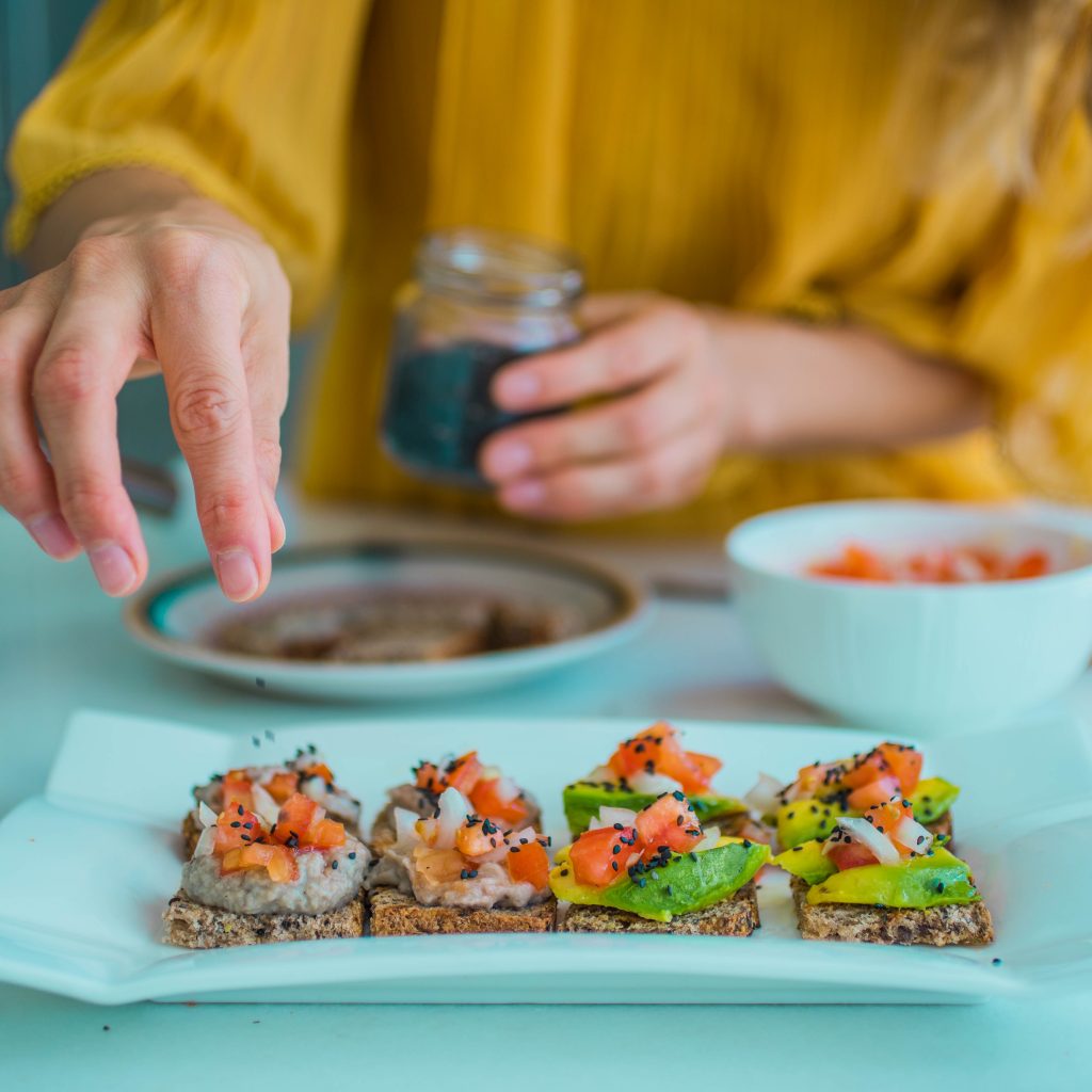 female hands arranging a plate with toasts with rice and avocado