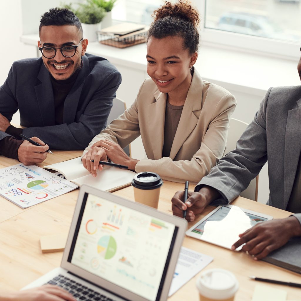 three your people on business attire on a conference table smiling to a 4th person