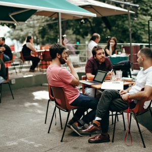 Three young men meeting outdoors at a coffee shop