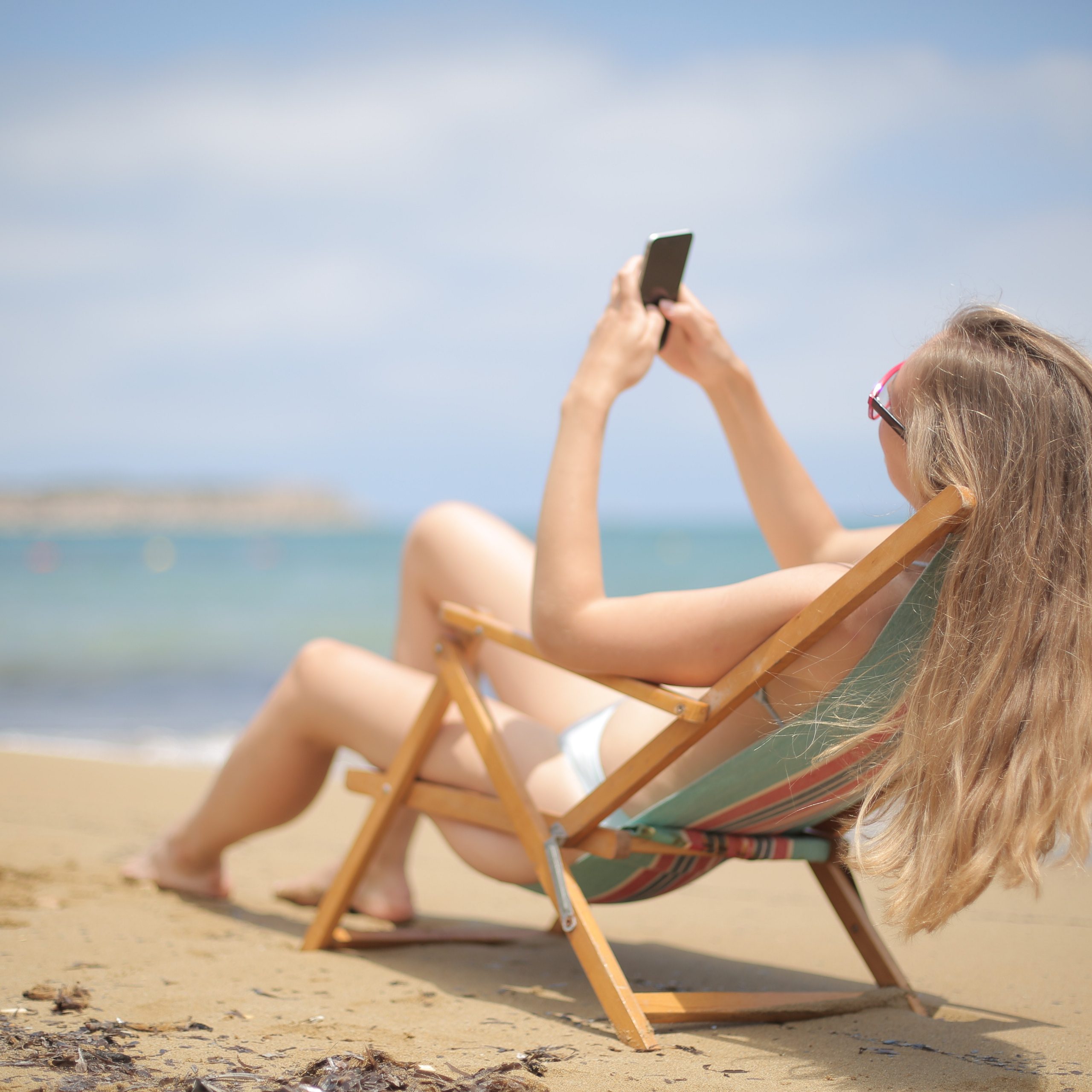 girl browsing phone at the beach